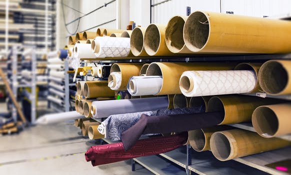 View inside an upholstery Edinburgh workshop with large rolls of fabric piled up on shelves.